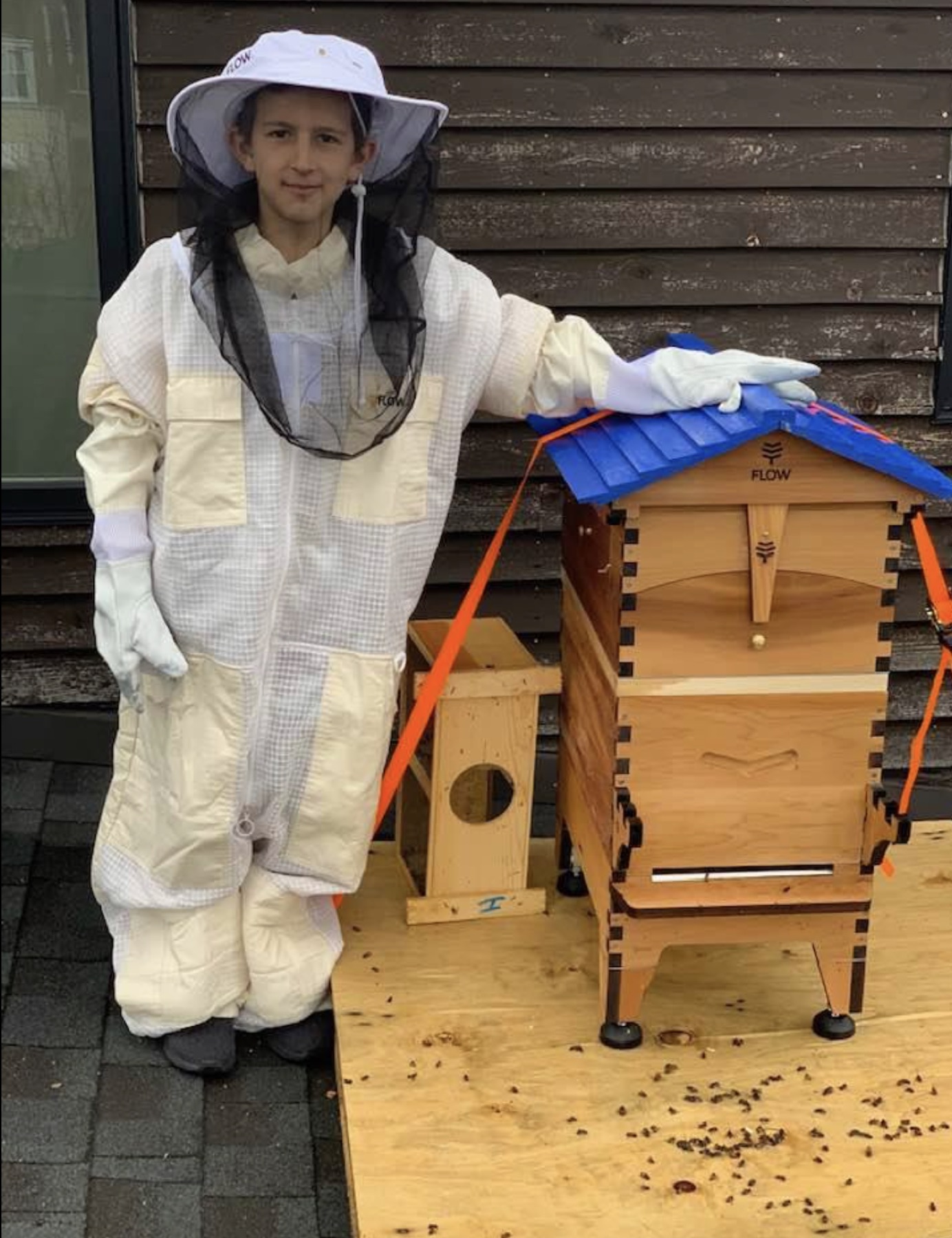 Rocco in a full beekeeping suit next to a hive