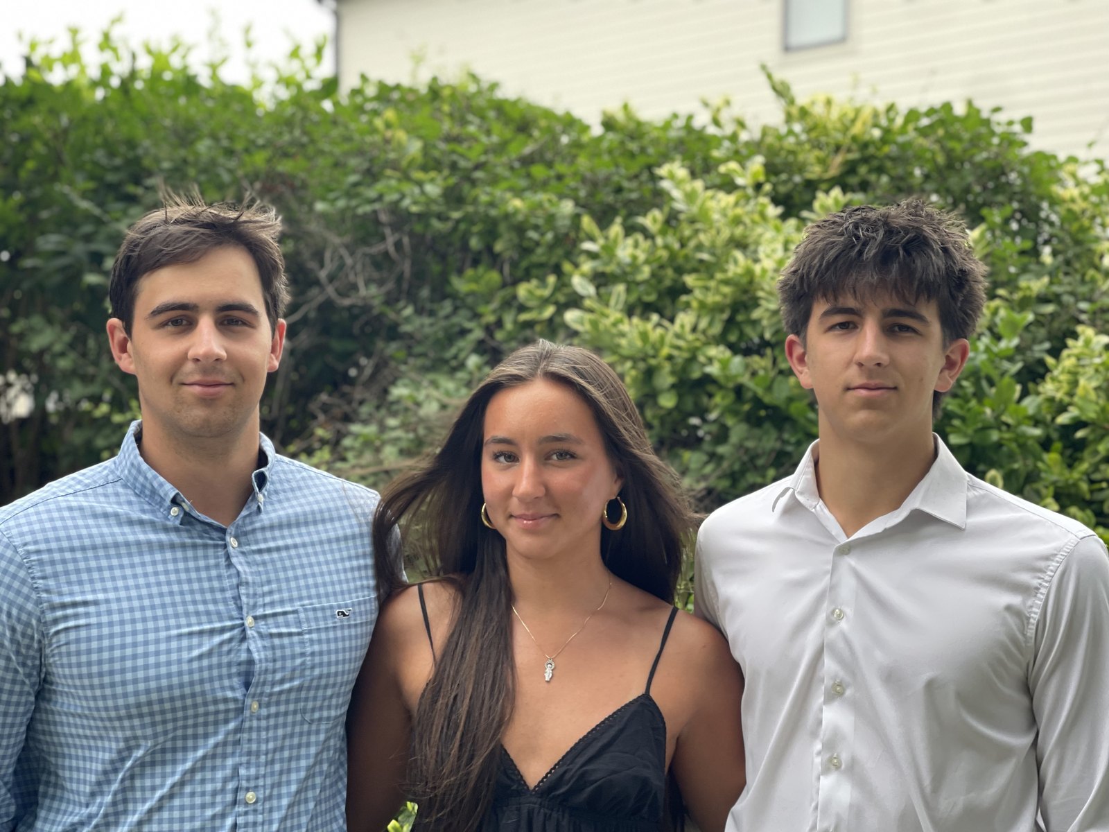 Rocco with his brother and sister standing in front of a hedge
